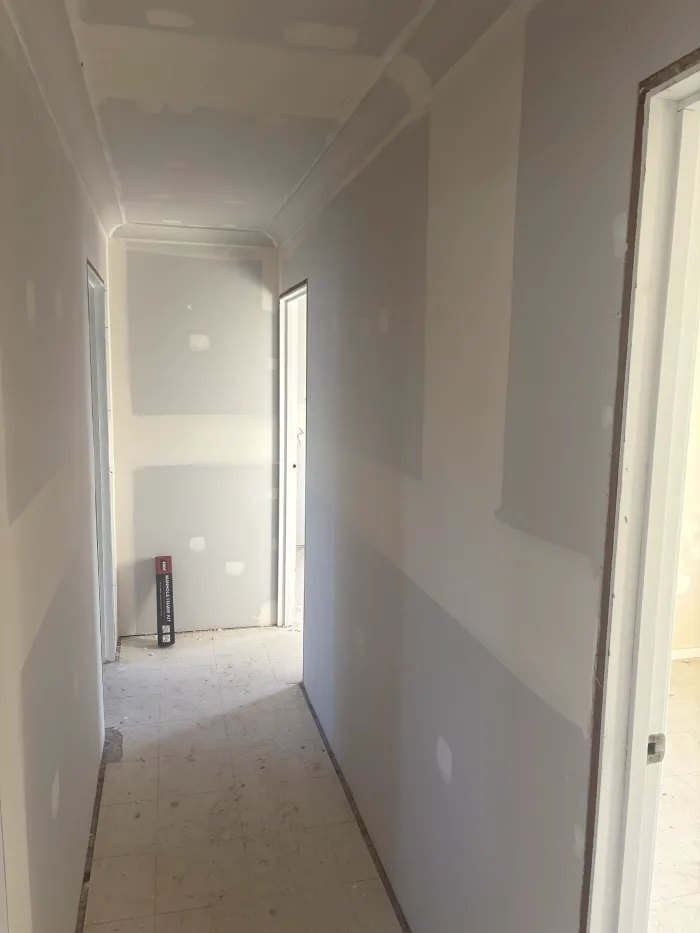 Plasterboard walls and ceiling through a hallway, set and finished ready for paint
